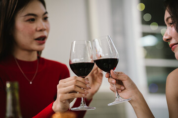 Two young women enjoying grilled food and wine together at an outdoor party, smiling and chatting in a relaxed, friendly atmosphere.