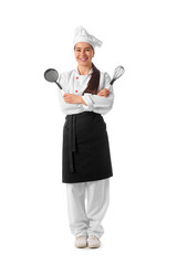 Young female chef with whisk and strainer spoon on white background