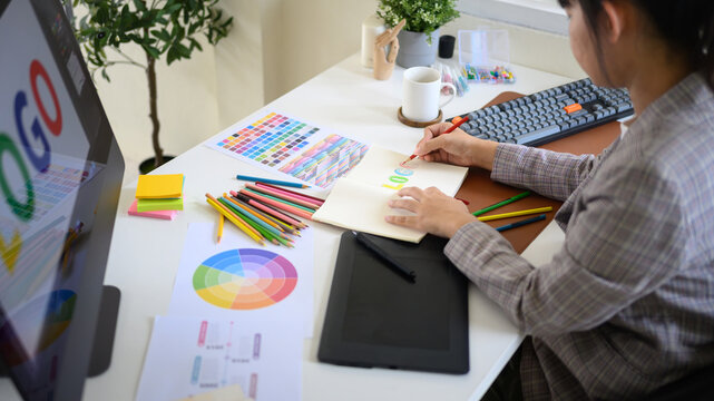 reative designer developing branding idea with color pencils, palette, and digital tablet