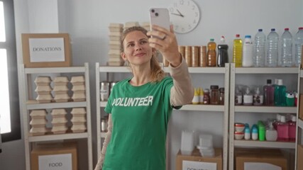 Woman uses hand to take selfie in a warehouse volunteer donation setting, smiling with blonde hair and young face against shelves. - Powered by Adobe
