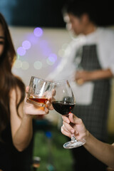Group of friends enjoying barbecue and wine together in a cozy outdoor party, smiling and chatting in a cheerful atmosphere.