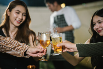 Group of friends enjoying barbecue and wine together in a cozy outdoor party, smiling and chatting in a cheerful atmosphere.