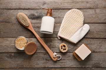 Composition with massage body brush, glove, soap bar and bowl with sea salt on wooden background