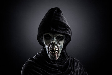 Portrait of a zombie with hooded cape over dark misty background