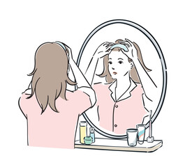 鏡の前でヘアバンドを止めるパジャマ姿の女性
