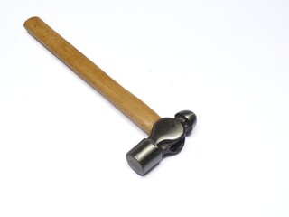 A ball-peen hammer with a wooden handle and polished steel head lies diagonally on a white background. A primary hand tool used for metalwork and general DIY projects.