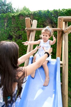 helping toddler to slide on playground in garden