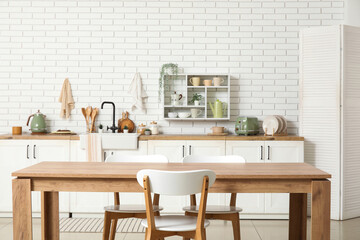 Interior of stylish kitchen with dining table, white counters and sink