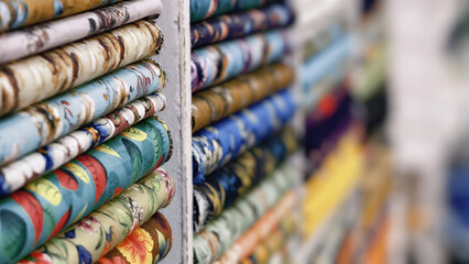 Closeup of colorful fabric rolls stacked on shelves in a textile shop