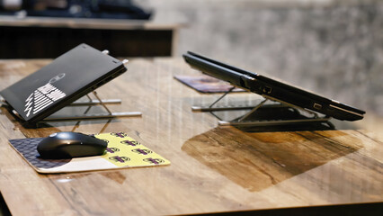 Two laptops on stands with a mouse and pad on a wooden desk © Mr. Shoaib Arshad 