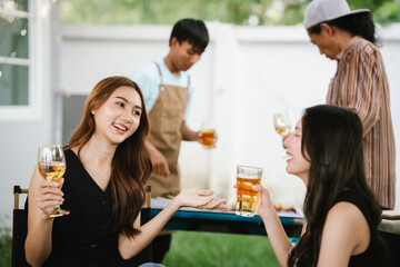 Group of friends enjoying barbecue and wine together in a cozy outdoor party, smiling and chatting in a cheerful atmosphere.