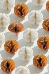 Top view of white beige honeycomb paper Christmas ornaments in minimal trend creative pattern on light background. New Year balls and one fungus with sun shadows, graphic layout modern holiday design.