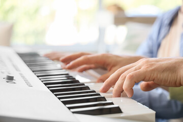 Private music teacher giving synthesizer lessons to boy at home, closeup