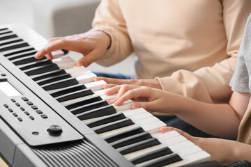 Fototapeta premium Cute boy taking synthesizer lessons from private music teacher at home, closeup