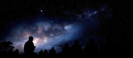 Fototapeta premium Silhouetted figures gaze at the night sky, revealing the Milky Way and a celestial display.
