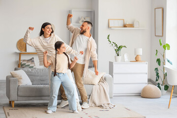 Cute little girl with her parents dancing at home
