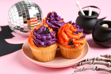 Disco ball with tasty cupcakes, skeleton hand and Halloween decor on pink background