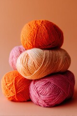A stack of colorful yarn balls against a peach background
