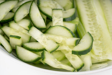 Cucumber cuts and slices in white bowl close up