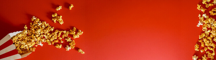 Popcorn spilling on a vibrant red background with copy space for website headers.