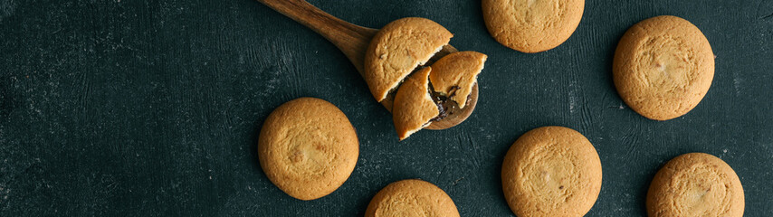 Cookies on a wooden spoon against a dark background.