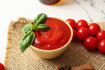 Bowl of tasty tomato sauce with basil leaves on white background, closeup