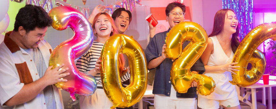 Business partners celebrate vibrant 2026 New Year office party with golden balloons, dancing, singing and confetti showers during festive nighttime celebration, sharing joyful moments and professional