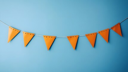 Festive orange triangular party banner hanging on light blue wall background