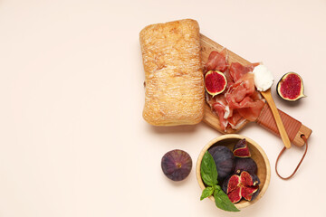 Wooden board with delicious prosciutto slices, ciabatta and bowl of fresh figs on beige background