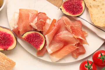 Board with delicious prosciutto slices, fresh fig and cherry tomatoes on white background