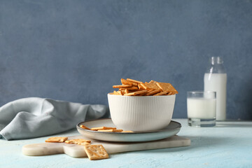 Composition with bowl of tasty crackers on blue grunge table