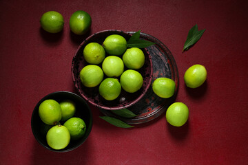 Bowls with fresh ripe limes on red background