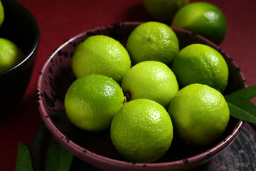 Bowl with fresh ripe limes on red background, closeup