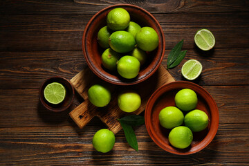 Bowls with fresh ripe limes on wooden background
