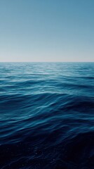 Fototapeta premium Vast Ocean Surface Under Clear Blue Sky with Gentle Waves