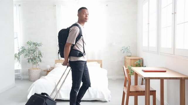 ホテルの部屋にスーツケースを持って立つ黒人男性旅行者