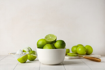 Bowl with fresh ripe limes on white tile table