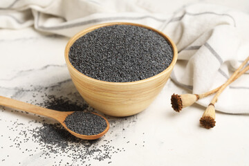 Bowl and wooden spoon with poppy seeds on white background, closeup
