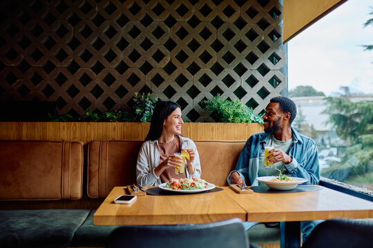 Happy couple smiling and talking during a restaurant lunch, celebrating enjoyment and connection over food and drinks