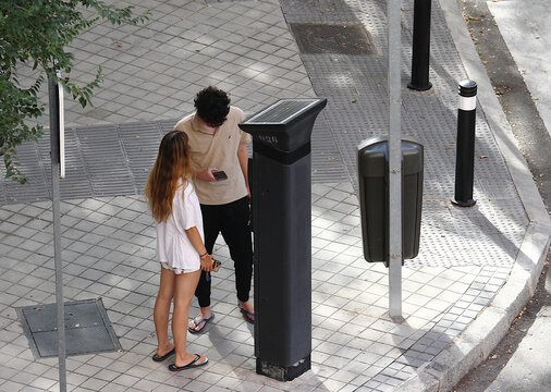 Parqu&iacute;metro y ticket de la hora zona ser en verano con dos j&oacute;venes pagando con el tel&eacute;fono m&oacute;vil