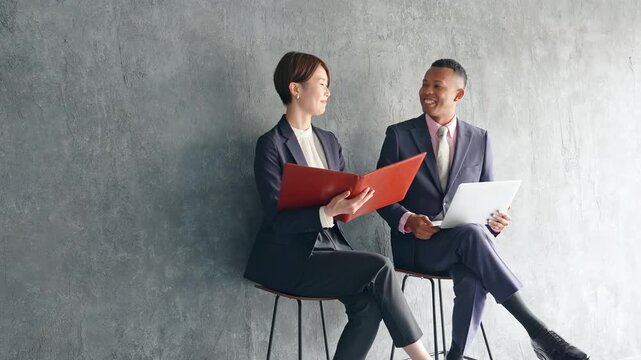 A black male businessman and a Japanese female staff member having a conversation in a stylish room