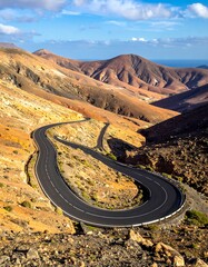 Winding road through arid mountain landscape, with ocean view