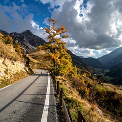 Winding road through mountains, autumn tree, dramatic sky