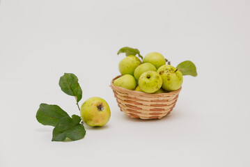 Green apples in a basket on a white background, selective focus