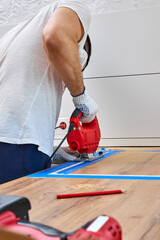 repairman using electric jigsaw and cutting hole for the sink in the kitchen countertops