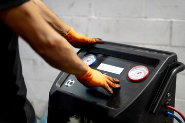 Mechanic servicing car air conditioning system in garage