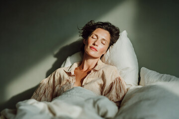 Woman sleeping peacefully in bed enjoying morning sunlight