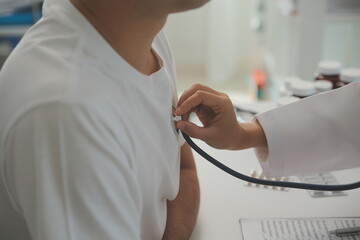 Young doctor is using a stethoscope listen to the heartbeat of the patient. Shot of a female doctor giving a male patient a check up