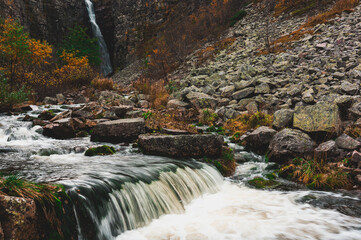 Majestic Njupeskär waterfall in Sweden flowing amidst vibrant autumn colors and rocky terrain