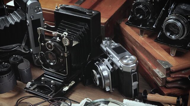 Old cameras in a composition on a wooden background, slowly moving in a horizontal plane.